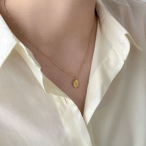 Close-up of a gold star pendant necklace on a model wearing a white shirt