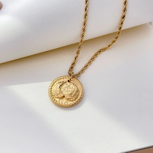 Détail du pendentif avec relief d'ailes en or 18K sur une chaîne en acier inoxydable torsadé