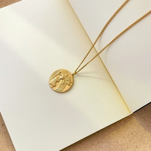 Détail du collier pendentif pièce dorée avec relief d'ange et texture de style punk chic
