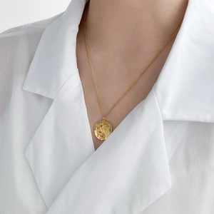 Détail d'un pendentif en forme de pièce à relief d'aile d'ange plaqué or 18 carats