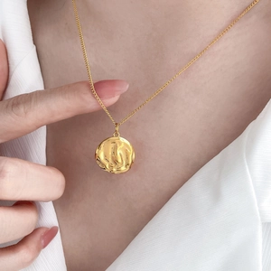 Détail du collier en titane plaqué or 18 carats avec pendentif rond texture lave