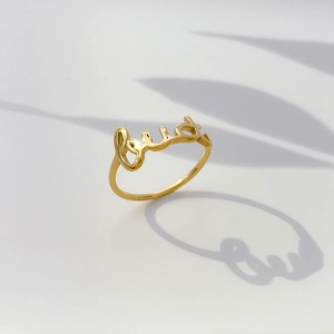 Macro de la bague dorée avec lettres cursives et jeux d'ombres de feuilles