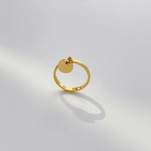 Gros plan d'une bague en acier doré avec un pendentif circulaire minimaliste et poli