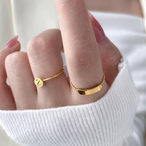 Détail d'une bague tressée dorée et d'une bague avec symbole Yin Yang au doigt