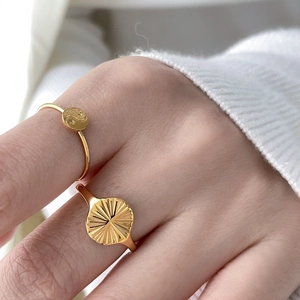 Gros plan d'une bague Tai Chi dorée et d'une bague à texture soleil sur modèle