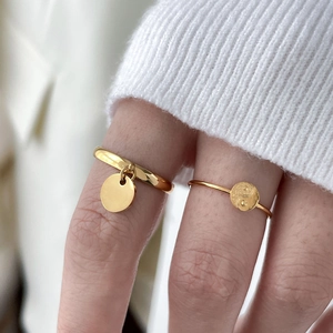 Gros plan de bagues dorées avec motif yin yang et pendentif circulaire sur modèle