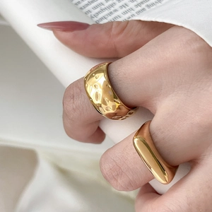 Close-up of gold titanium steel rings with textured lava effect and polished finish