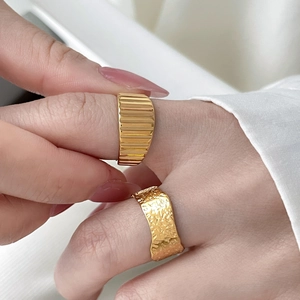 Detail of 18K gold plated rings featuring vertical stripes and hammered crater textures
