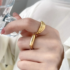 Close-up of 18K gold-plated titanium steel rings with textured vertical stripes and smooth finish
