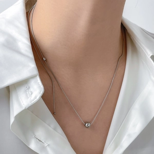 Collier chaîne serpent avec perles argentées porté sur une chemise blanche chic