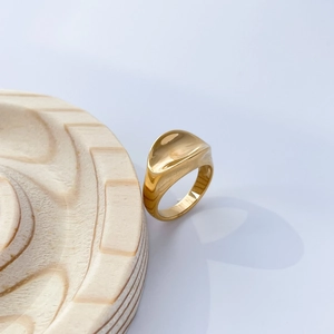Detailed close-up of a wide 18K gold plated concave wave ring on a wooden display stand