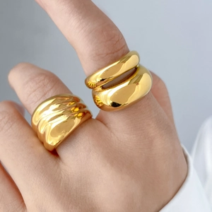 Close-up of chunky gold-plated wide band and layered rings on model with high-polish finish