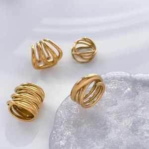 Detail of four multi-layer intertwined geometric gold rings with polished finish