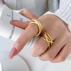 Detail of layered gold curves and intertwined line rings on hand with minimalist aesthetic