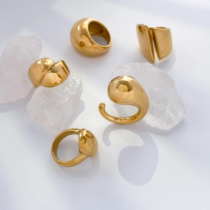 Five minimalist gold chunky titanium rings with organic curved shapes on white rocks