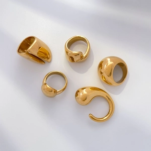 Detailed close-up of chunky gold titanium steel rings with fluid organic droplet shapes