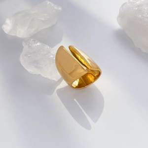 Detailed view of wide gold mirror-polished stainless steel ring with abstract arched design
