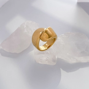Macro shot of gold wide band ring with overlapping fold design on white crystal