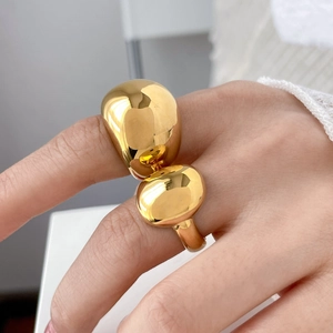 Macro shot of polished gold metallic sphere ring with minimalist bold crossover design