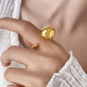 Detail of chunky gold open ring with large metallic sphere and teardrop geometric design