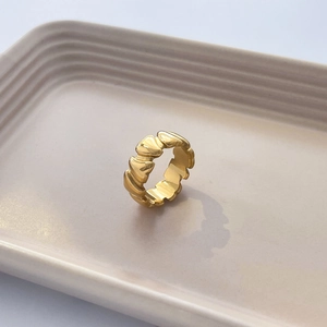 Détail d'une bague plaquée or 18K avec texture ondulée sur un plateau en céramique