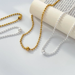 Minimalist silver and gold beaded necklace featuring a large polished central metal bead