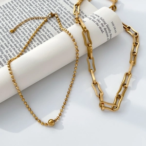 Detail of gold beaded chain and chunky link necklace set on vintage book paper background