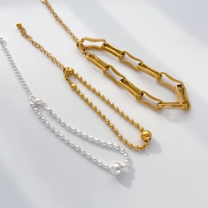 Detailed view of minimalist gold and silver bead necklaces with ball pendants and lobster clasps