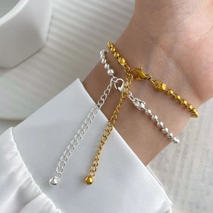 Macro shot of silver and gold beaded bracelets with lobster clasp and extension chain