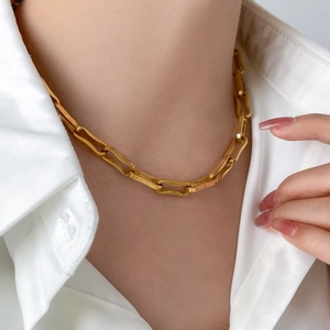 Close-up of a chunky gold plated rectangular link chain necklace on a white shirt