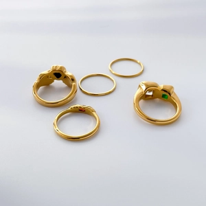 Detail of five-piece gold plated ring set with red, green and black gemstones