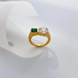 Macro detail of gold-plated wide ring with emerald and clear rectangular zircons