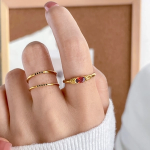 Detail of gold rings featuring red oval gemstone and black micro-diamonds on fingers