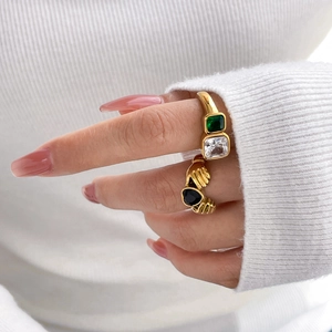 Detail of vintage gold rings with square emerald, clear crystal and black heart hands motif