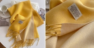 Macro view of yellow and beige double-sided cashmere scarf with tassels and fabric label