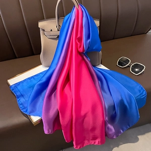 Detail of pink and blue gradient satin silk scarf draped on a luxury leather handbag