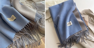 Detail of sky blue and light grey double-sided scarf with tassels and brand label