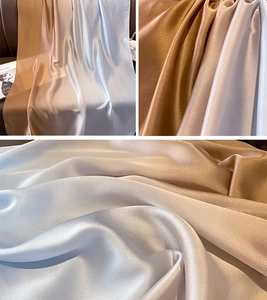 Detail of silk-like satin fabric in gradient champagne, silver, and bronze tones