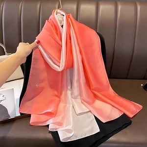 Close-up of smooth coral pink and beige gradient satin silk scarf with glossy texture