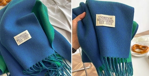 Detail of double-sided cashmere scarf in blue and green with fringe and woven label