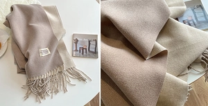 Macro view of high-density cashmere texture and beige-brown fringe detail on scarf