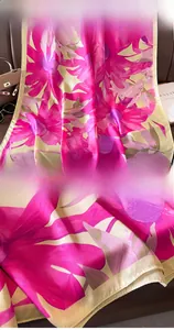 Detailansicht eines Seidenschals mit Blumenmuster auf einem Ledersofa mit Luxus-Accessoires