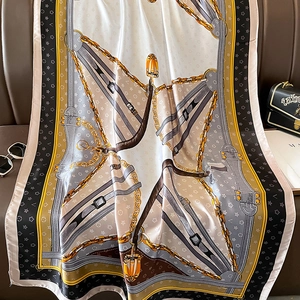 Luxurious chain print square silk scarf with gold belt buckle pattern on leather sofa