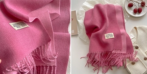 Detail of pink faux cashmere scarf showing fabric texture, woven label and tassels