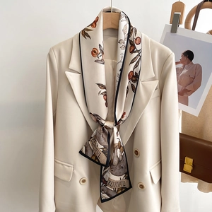 Elegant ivory silk scarf with retro nature prints and black border on a cream blazer