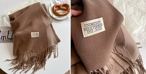 Detail of dark brown cashmere-like scarf showing twill texture, tassels and woven label