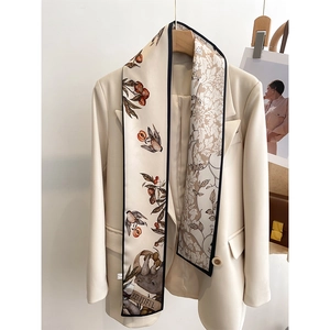 Detail of floral paisley silk scarf draped on a cream suit jacket showing artistic bird prints