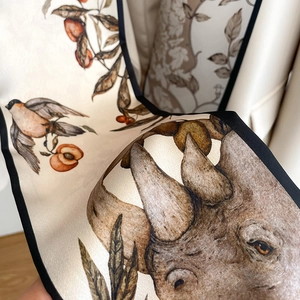 Detailed close-up of premium silk scarf featuring wildlife prints and elegant black edges