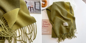 Detail of olive green cashmere-like scarf showing fringe and soft knit texture
