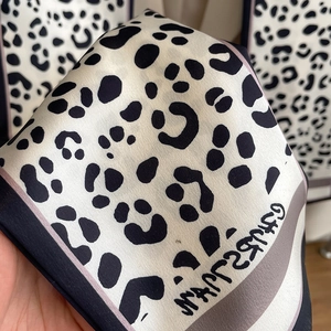 Detail of silk-like leopard print scarf with black borders and smooth satin texture